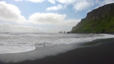 Reynisfjara 'nın siyah kumsalında dalgalar İzlanda' nın güneyindeki Vik sahiline vuruyor..