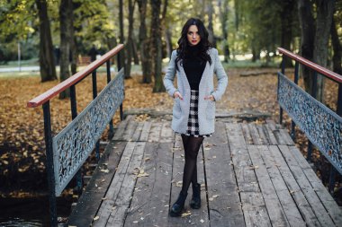 Genç kadın sonbahar parkında yürüyor.