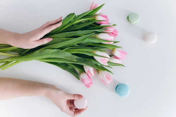 Händer som håller tulpaner och macaron — Stockfoto