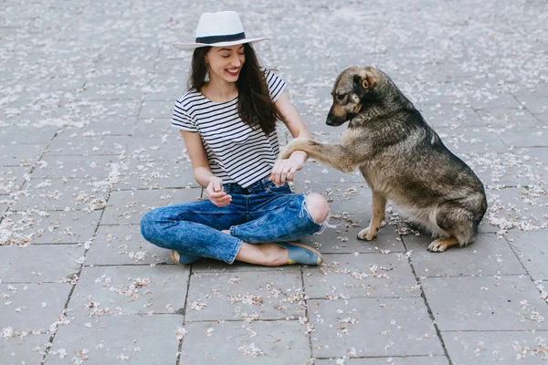 Девушка играет с бездомной собакой — стоковое фото