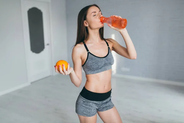 Girl holding orange and drink water — Stock Photo, Image