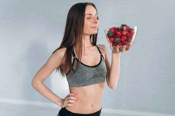 Fitness-Mädchen hält Erdbeeren in der Hand — Stockfoto