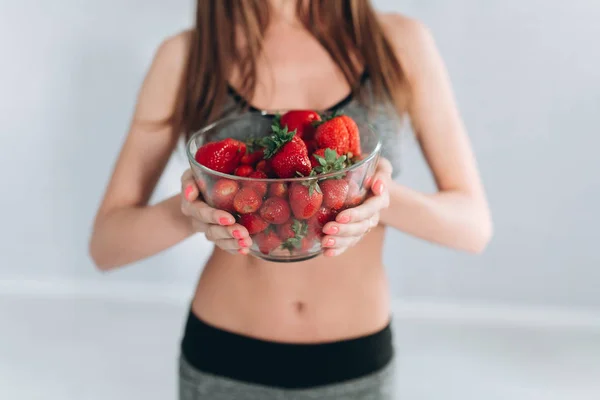 Fitness girl holding strawberries — Stock Photo, Image