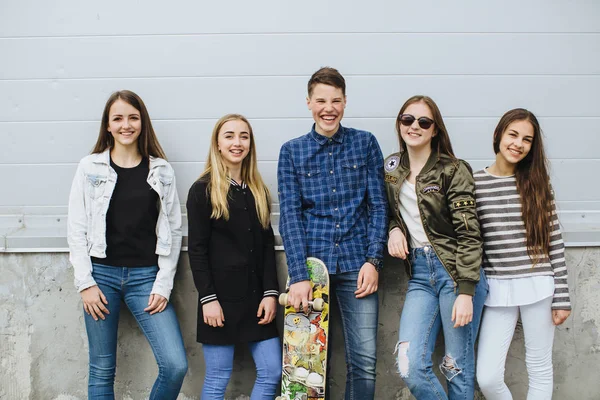 Adolescentes sorridentes com skate pendurado fora — Fotografia de Stock