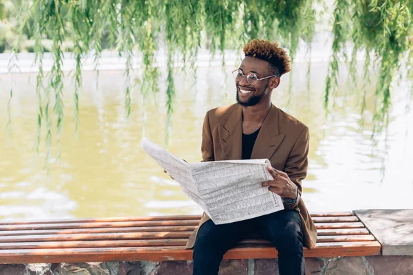 Man i en jacka med en tidning av sjön — Stockfoto