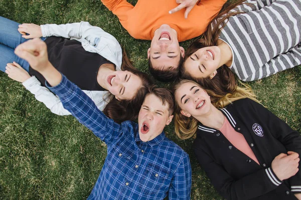 Teenageři, ležící na trávě v létě — Stock fotografie