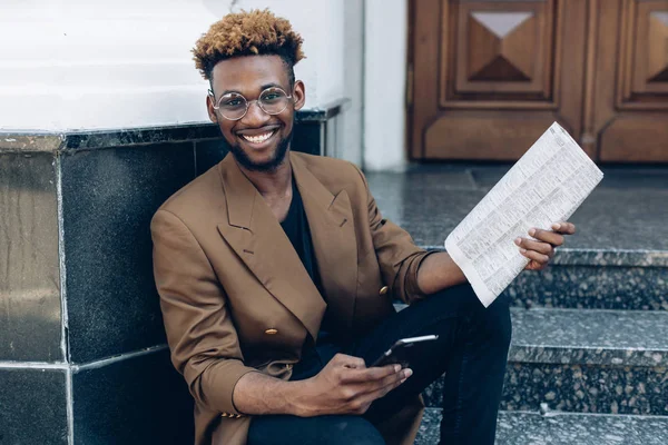 Man i en jacka med telefon och tidningen i city — Stockfoto