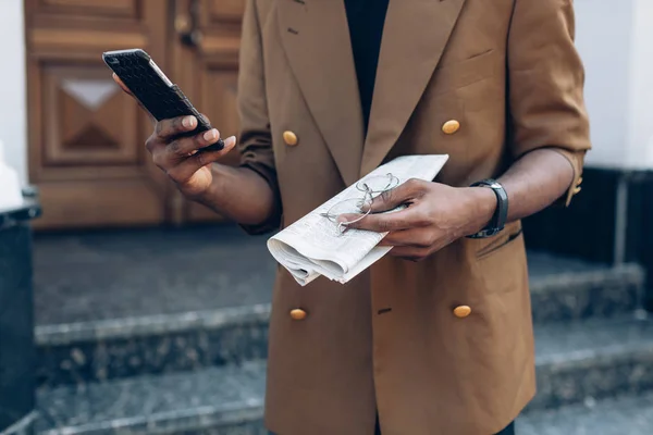 Man i en jacka med telefon och tidningen i city — Stockfoto