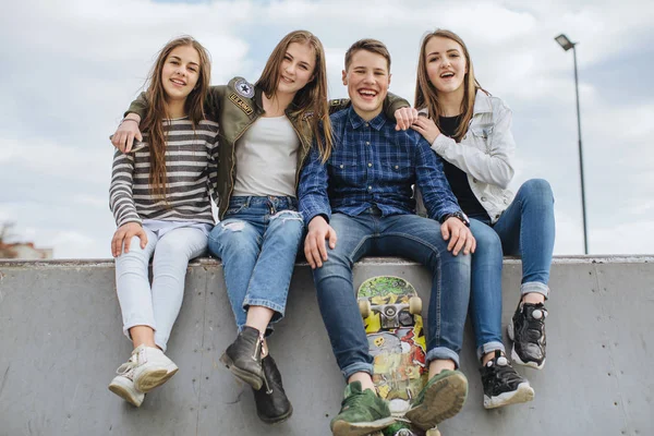 Adolescentes sorridentes com skate pendurado fora — Fotografia de Stock