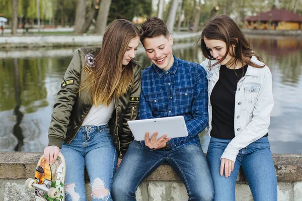 Smiling teenagers hanging out outside with tablet — Stock Photo, Image