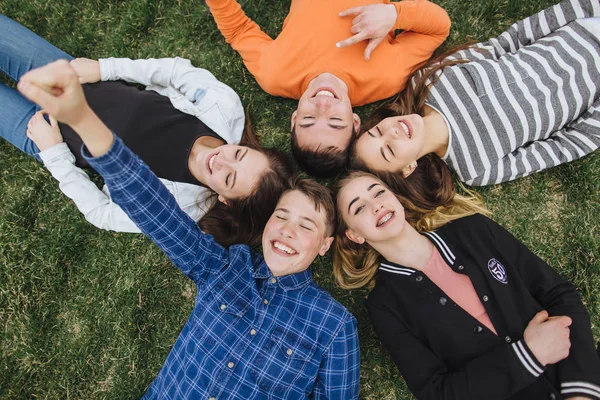 Teenageři, ležící na trávě v létě — Stock fotografie