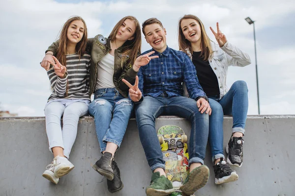 Adolescentes sorridentes com skate pendurado fora — Fotografia de Stock