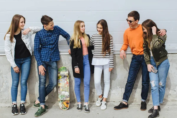 Adolescentes sorridentes com skate pendurado fora — Fotografia de Stock