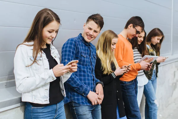 Grupp tonåringar utomhus med mobiltelefoner — Stockfoto