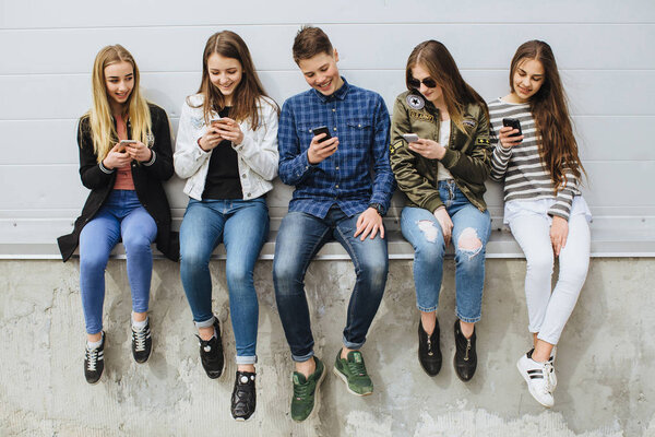 Группа подростков на улице с мобильными телефонами
