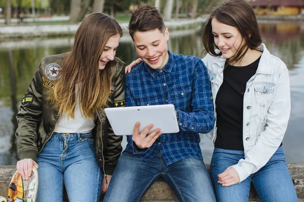 Smiling teenagers hanging out outside with tablet — Stock Photo, Image