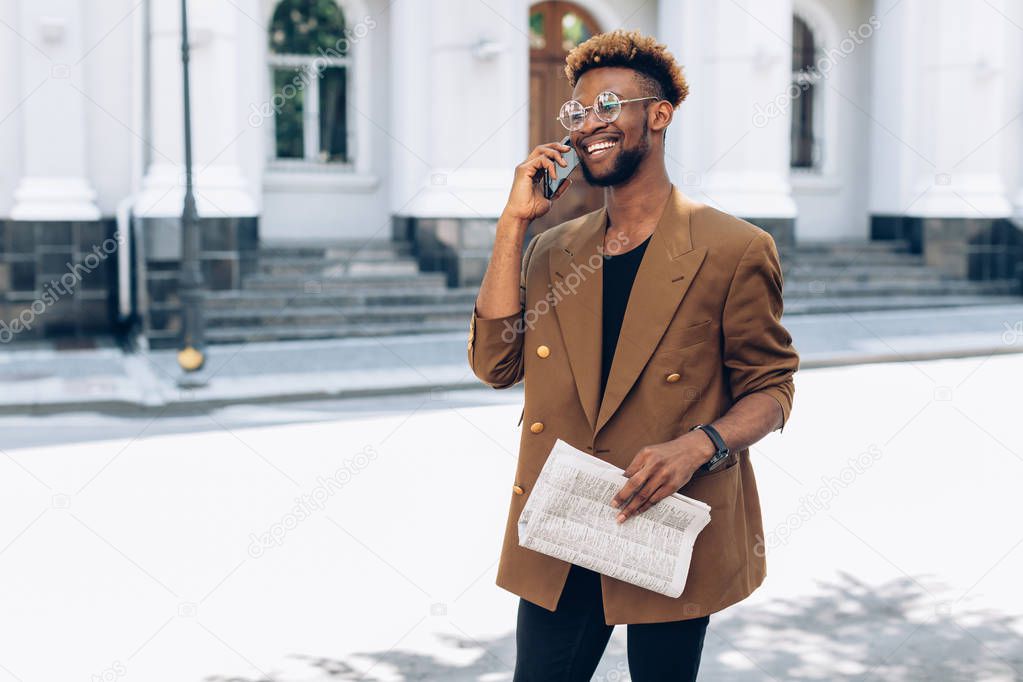 Man in a jacket with phone and newspaper in city
