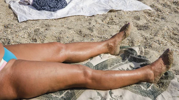 Gebräunte nasse weibliche Beine am Strand — Stockfoto
