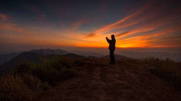 Silhueta de um homem tirando fotos ao pôr do sol — Fotografia de Stock