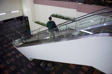 Yürüyen merdivenlerden aşağı bavul turist kızla.