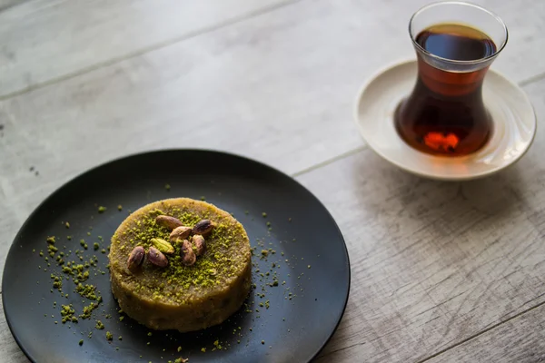 Turecký dezert irmik helvasi s pistáciovou prášek a čaje. — Stock fotografie