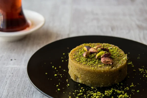 Turkish Dessert irmik helvasi with pistachio powder and tea. — Stock Photo, Image