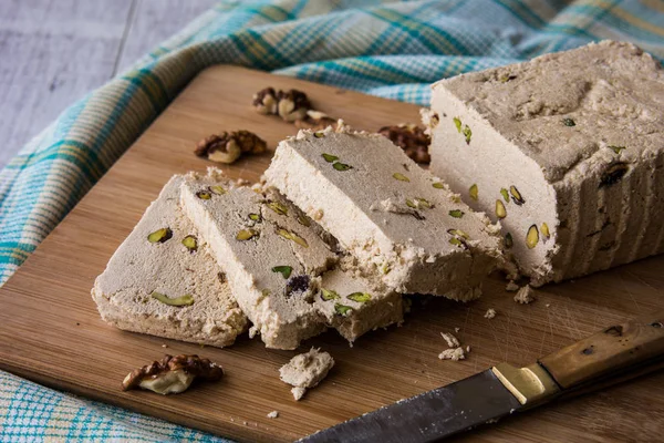 Slices of Halva with peanut and walnut on a wooden surface. — Stock Photo, Image