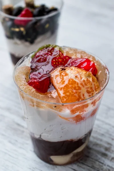 Шоколадные конфеты и смешанные фрукты Парфе с йогуртом в стеклянной чашке — стоковое фото