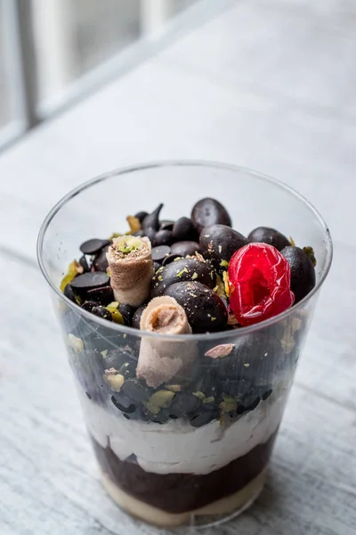 Шоколадные конфеты и смешанные фрукты Парфе с йогуртом в стеклянной чашке — стоковое фото