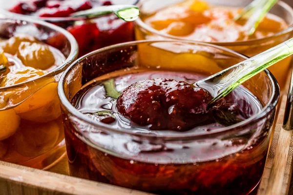 Confiture de fraises dans un bol en verre avec cuillère et diverses marmelades — Photo