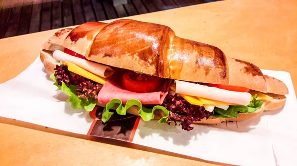 Sandwich de croissant con jamón, queso cheddar, tomate cherry y verduras . — Foto de Stock