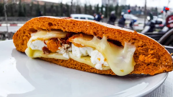 Sandwich con queso feta derretido y tomate seco en la ciudad. (pan de naranja ) —  Fotos de Stock