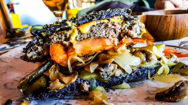 Black Burger with cheddar cheese, mushrooms and pickle. (cut half burger) — Stock Photo, Image