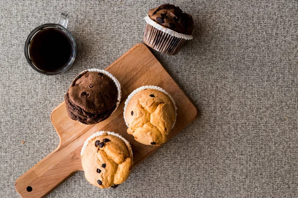 Muffins de chocolate y vainilla con café en superficie de madera . —  Fotos de Stock
