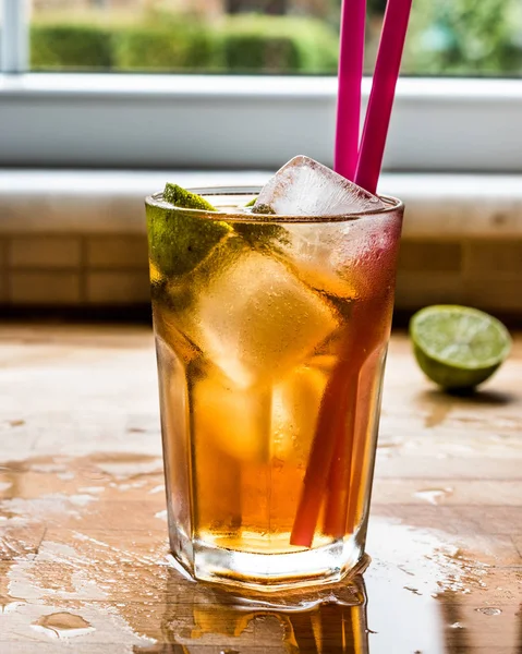 Long Island cocktail di tè freddo con lime, ghiaccio e servito con paglia rosa — Foto Stock