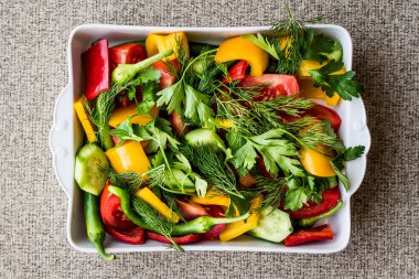 Dereotu, sarı biber, kırmızı biber, maydanoz, domates ve salatalık beyaz kase salata.