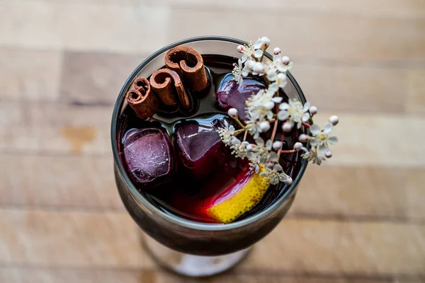 Sangria Cocktail in wine glass with lemon, cinnamon, fruits and ice.