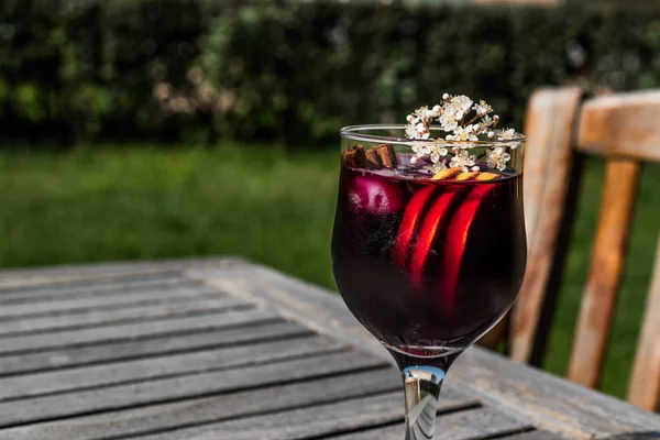 Sangria Cocktail in wine glass with lemon, cinnamon, fruits and ice.