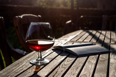 Cam konyak Garden (doğal ışık ahşap yüzeyde bir kitapla).