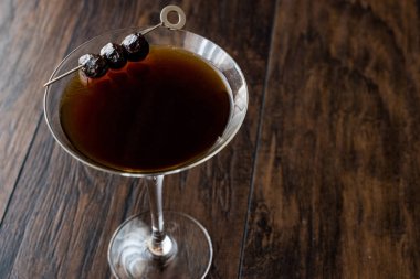 Siyah Manhattan kokteyl koyu ahşap yüzey üzerinde zeytinli.