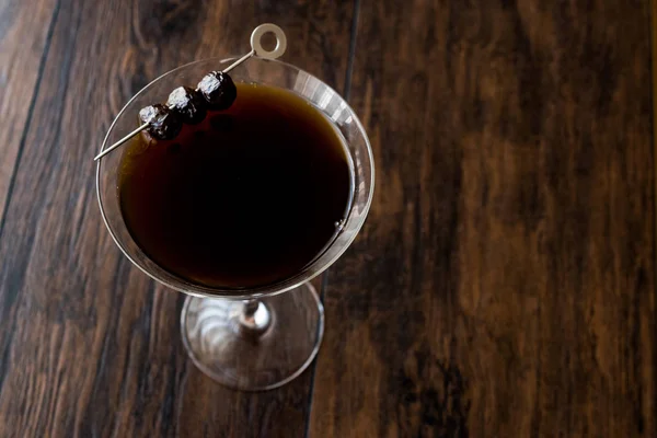 Black Manhattan Cocktail com azeitonas na superfície de madeira escura . — Fotografia de Stock