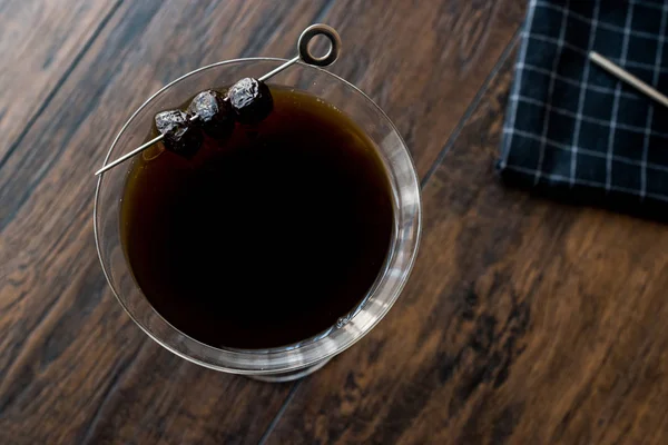 Чорний Манхеттен коктейль з оливками на темні дерев'яні поверхні. — стокове фото