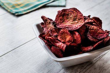 Mor pişmiş pancar cips beyaz tahta yüzeyi.