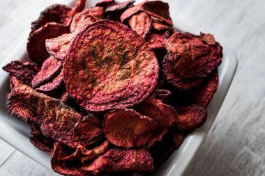 Mor pişmiş pancar cips beyaz tahta yüzeyi.