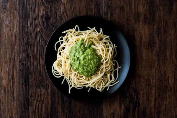 Spaghetti with pesto sauce on dark wooden surface. — Stock Photo, Image
