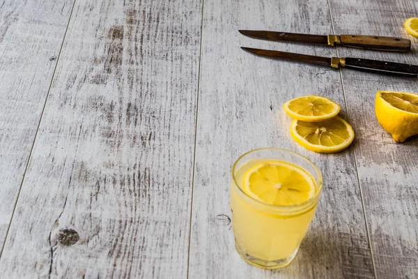 Licor de limón Limoncello con limón sobre superficie de madera blanca . —  Fotos de Stock