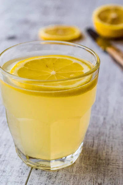 Licor de limón Limoncello con limón sobre superficie de madera blanca . —  Fotos de Stock