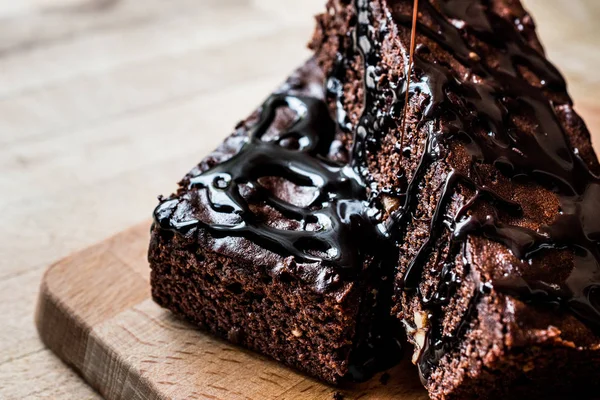 Brownie torta csokoládé öntettel, fa felületre. — Stock Fotó