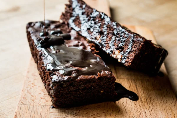 Ahşap yüzey üzerinde çikolata soslu brownie kek.