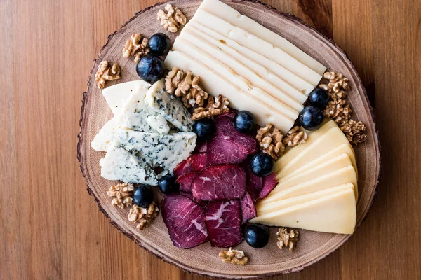 Peynir tabağı füme et, ceviz ve üzüm ahşap yüzeyi ile